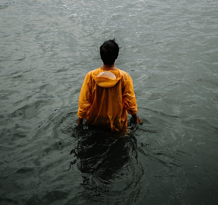 back view of man wearing yellow hoodie standing in the water