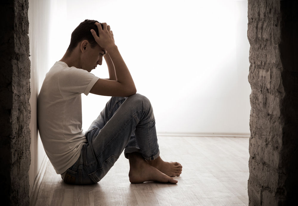 a man sitting on the floor while holding his head