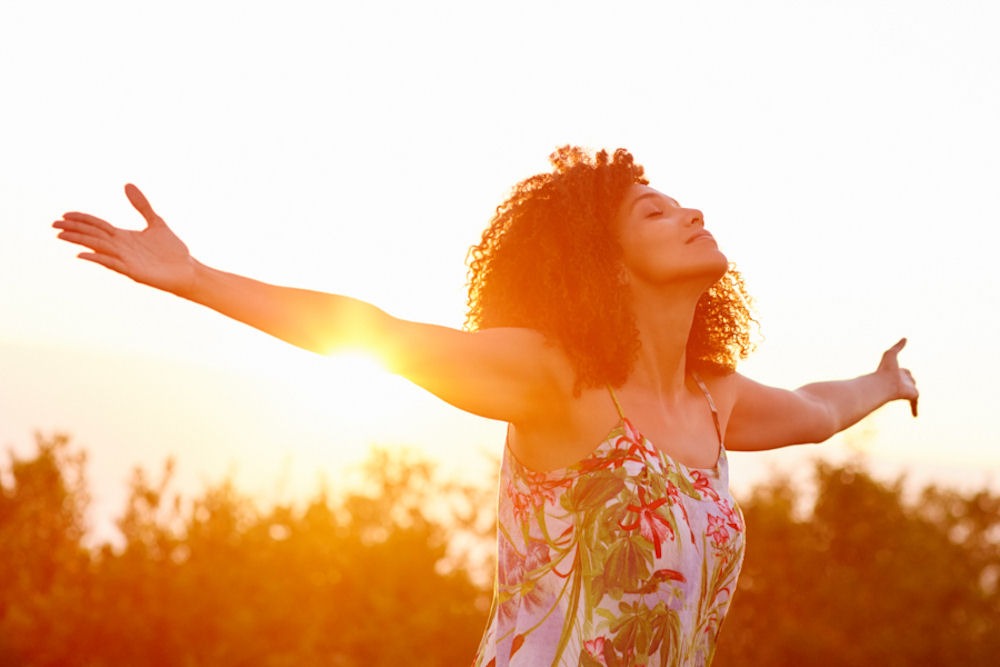 A woman embracing sunlight, representing the uplifting effects of happy pills