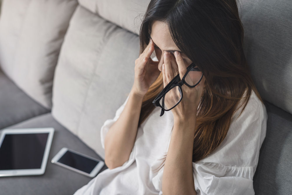 Stressed woman rubbing her eyes, possibly experiencing the effects of alcohol and cortisol imbalance