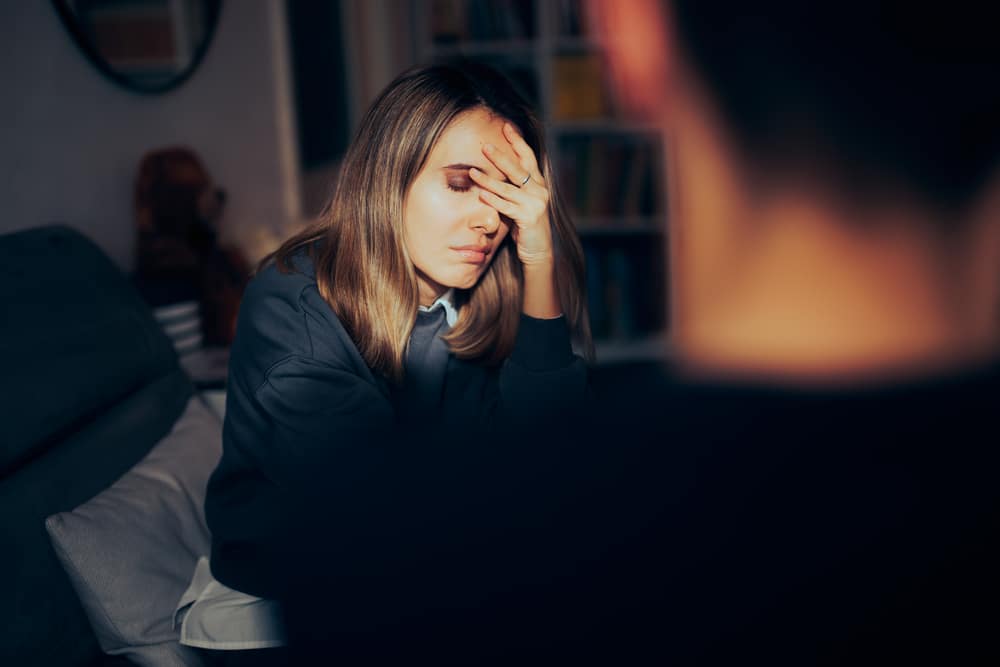 A woman with her head in her hands, illustrating the emotional impact of addiction and the need for DMT Addiction Treatment in Orange County.