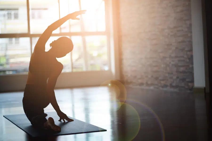 A person practicing yoga in a sunlit room, representing the healing and mindfulness practiced in Ecstasy Addiction Treatment in Orange County.